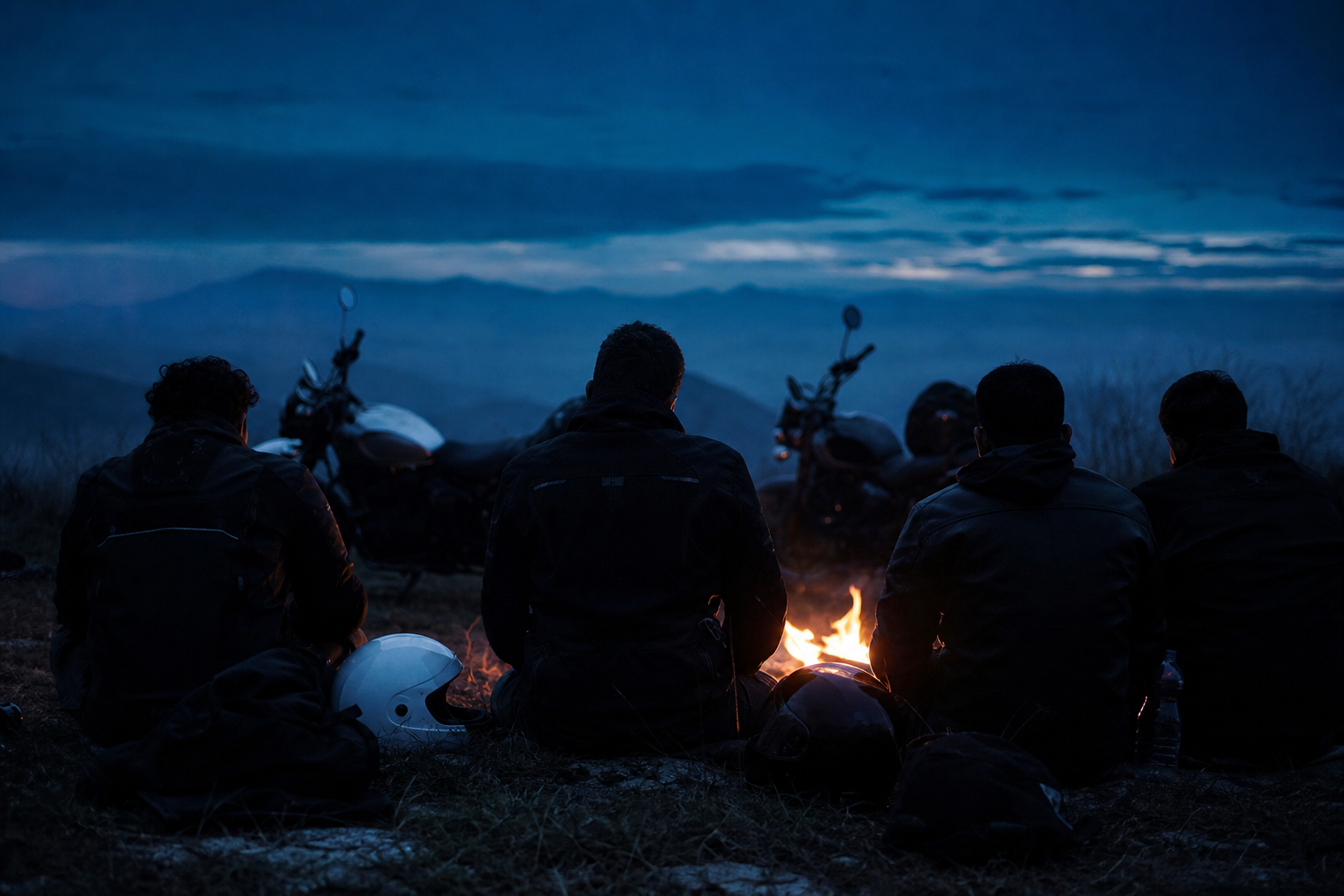 Riders gathered around a campfire before sunrise, photographed from behind